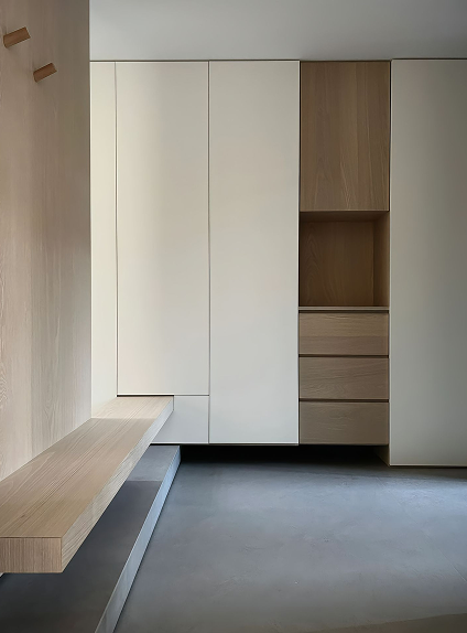 Interior de armario y banco de madera en tonos claros, con un diseño moderno y funcional, destacando la simplicidad de las líneas y los acabados de alta calidad en un espacio minimalista.